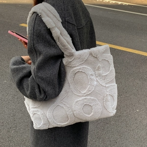 Detail of soft cream plush tote bag with embossed circular patterns and wide strap