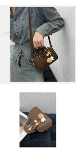 Detail of brown litchi grain leather Boston bag with decorative charm and dual handles