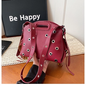 Dettaglio borsa in pelle bordeaux con occhielli argentati e nappine decorative