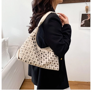 Détail d'un sac à bandoulière blanc crème avec rivets métalliques et large sangle