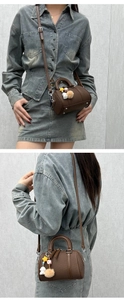 Vue détaillée du sac Boston marron avec breloques d'étoiles et pompon sur tenue denim