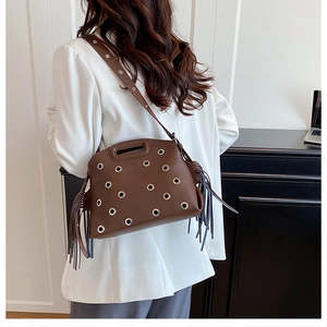 Dettaglio borsa in pelle marrone vintage con occhielli in argento e frange laterali