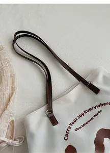 Λεπτομέρεια υφασμάτινης τσάντας με καφέ δερμάτινα λουράκια και καλλιτεχνική εκτύπωση