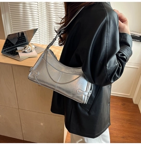 Primer plano de bolso de hombro plateado metálico con cadena en una modelo
