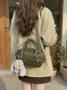 Olive green patent leather bowling bag with belt buckle detail and plush rabbit charm