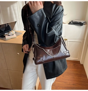 Detalle del bolso de hombro en cuero marrón oscuro con cadena plateada y acabado brillante