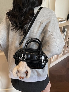 Fashionable black patent leather handbag with plush rabbit charm and silver metal hardware