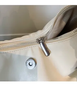 Makroaufnahme der weißen Ledertasche mit silbernem Reißverschluss und Fischgrät-Innenfutter