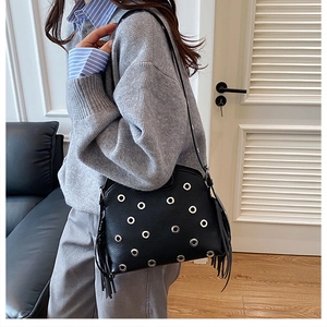 Dettaglio borsa in pelle martellata nera con occhielli argento e lunghe nappe laterali
