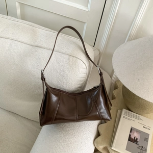 Close-up of retro dark brown hobo bag on white sofa with silver buckle detail
