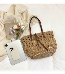 Detail of hollow woven straw tote bag featuring leather handles and large capacity storage
