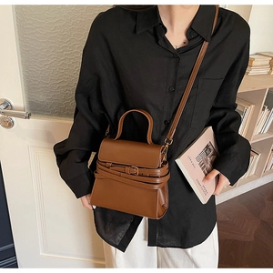 Détail d'un sac bandoulière en cuir marron avec sangle réglable et boucle élégante