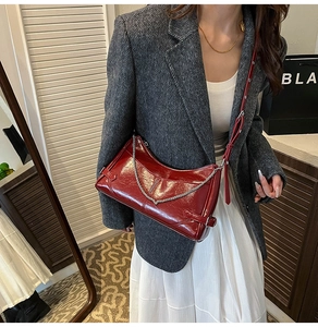 Détail du sac sous l'aisselle en cuir ciré rouge foncé avec chaîne et texture brillante