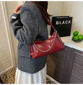 Detalle del bolso de hombro en cuero rojo brillante con cadena plateada y hebilla lateral