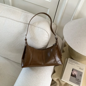 Close-up of vintage brown pleated leather bag on a white sofa with home decor