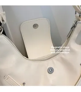 Detailansicht des Magnetverschlusses und Reißverschlusses einer cremeweißen Handtasche