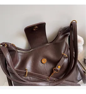 Detail of vintage dark brown leather tote with antique metal hardware and plush ball charm