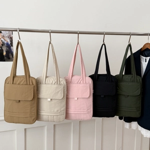 Detailed macro view of quilted nylon tote bags in five colors with vertical stitching
