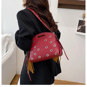 Dettaglio borsa in pelle rossa con anelli d'argento e lunghe nappe gialle