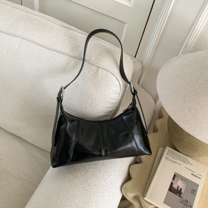 Detail of black glossy leather underarm bag with silver buckle and vertical stitching
