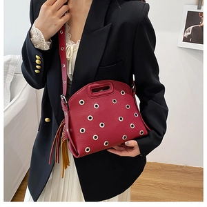 Dettaglio borsa in pelle rossa con occhielli argentati e lunghe nappe laterali