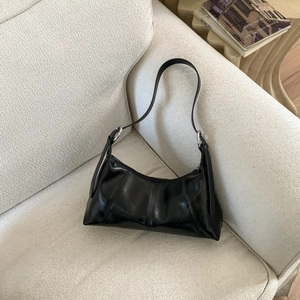 Macro detail of black glossy leather stitching and silver hardware on a shoulder bag