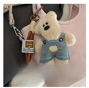Détail d'un porte-clés ours en peluche avec salopette sur un sac à main rose