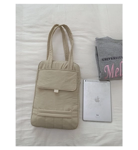 Detail view of khaki quilted tote bag with front pocket and multi-compartment interior