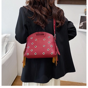 Dettaglio borsa in pelle martellata rossa con occhielli argento e nappe gialle