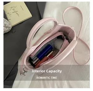 Capacité interne du sac seau en cuir rose avec pochette et objets du quotidien