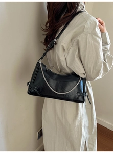 Détail du sac bandoulière en cuir noir avec chaîne argentée et boucle sur le côté