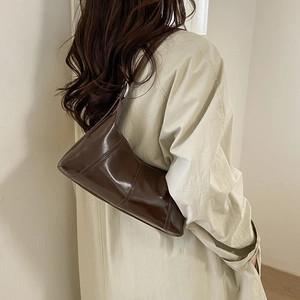 Deep brown glossy shoulder bag styled with a minimalist beige trench coat outfit