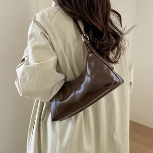 Detail view of the sleek dark brown leather underarm bag with silver ring hardware