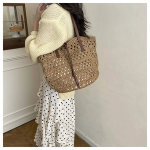 Detailed macro view of woven straw texture and durable brown leather handles on tote bag