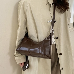 Detail of dark brown faux leather shoulder bag with sleek stitching and metal rings