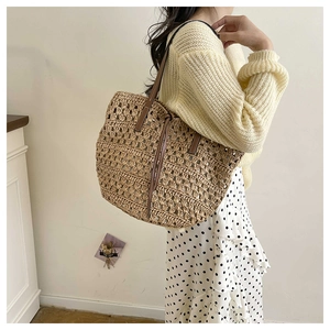 Detail of hollow woven tote bag with brown leather handles and drawstring closure