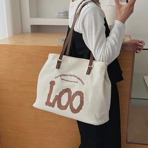 Detail of cream canvas tote bag with brown leather strap and artistic text print