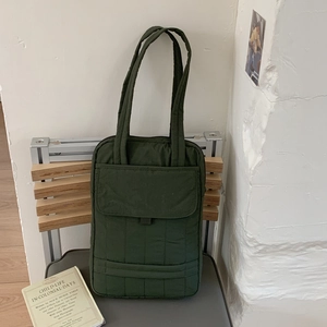 Detail of dark green quilted crossbody bag with a large functional front flap pocket