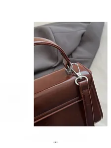 Detail shot of silver metal hook and glossy chocolate leather on the crossbody bag handle