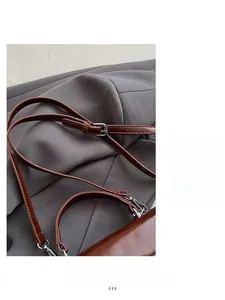 Detail of adjustable brown leather shoulder strap and silver buckle on a square bag