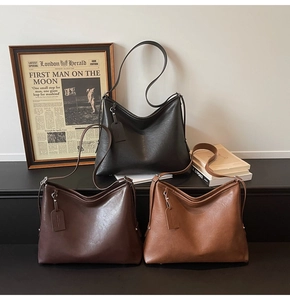 Detailed side view of three vintage leather tote bags with metal studs and hangtags