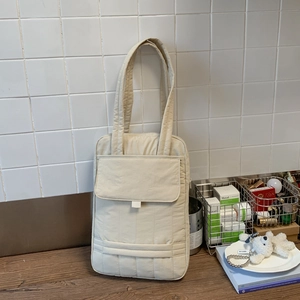 Detailed view of the quilted texture and large front flap pocket on a cream crossbody bag