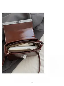 Top-down detail of brown vintage handbag interior showing phone and lipstick storage