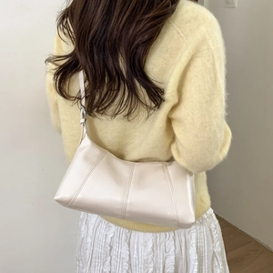 Back view of model wearing a cream shoulder dumpling bag with stitched details