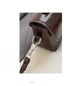 Detailed macro view of dark brown faux leather bag with silver metallic swivel buckle