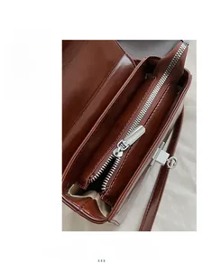 Detailed close-up of a dark brown square bag with smooth silver zipper and heart key charm