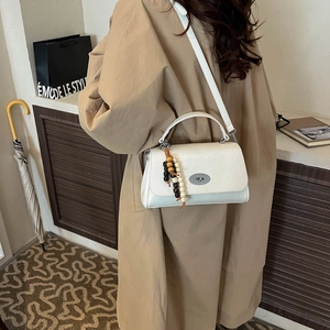 White textured leather crossbody bag with silver oval twist lock and wooden bead charm detail