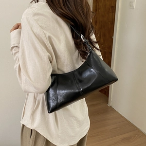 Detail of black glossy patent leather shoulder bag with silver metal buckles