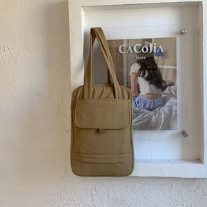 Detail of khaki quilted tote bag featuring a front flap pocket and ribbed texture