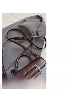 Detail of dark brown leather handbag with large decorative buckle on a grey suit jacket
